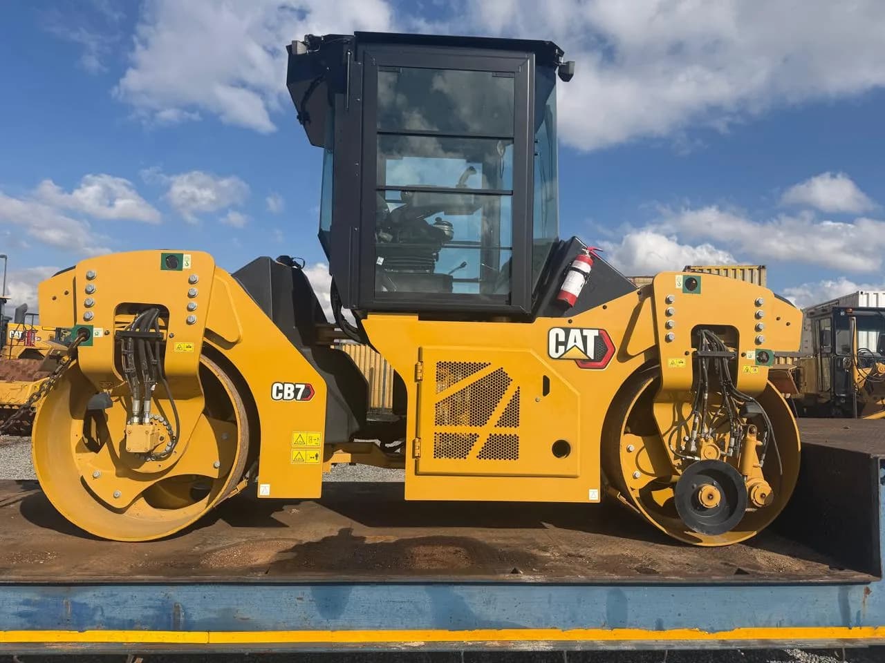 A Caterpillar CB7 tandem roller on a truck bed.