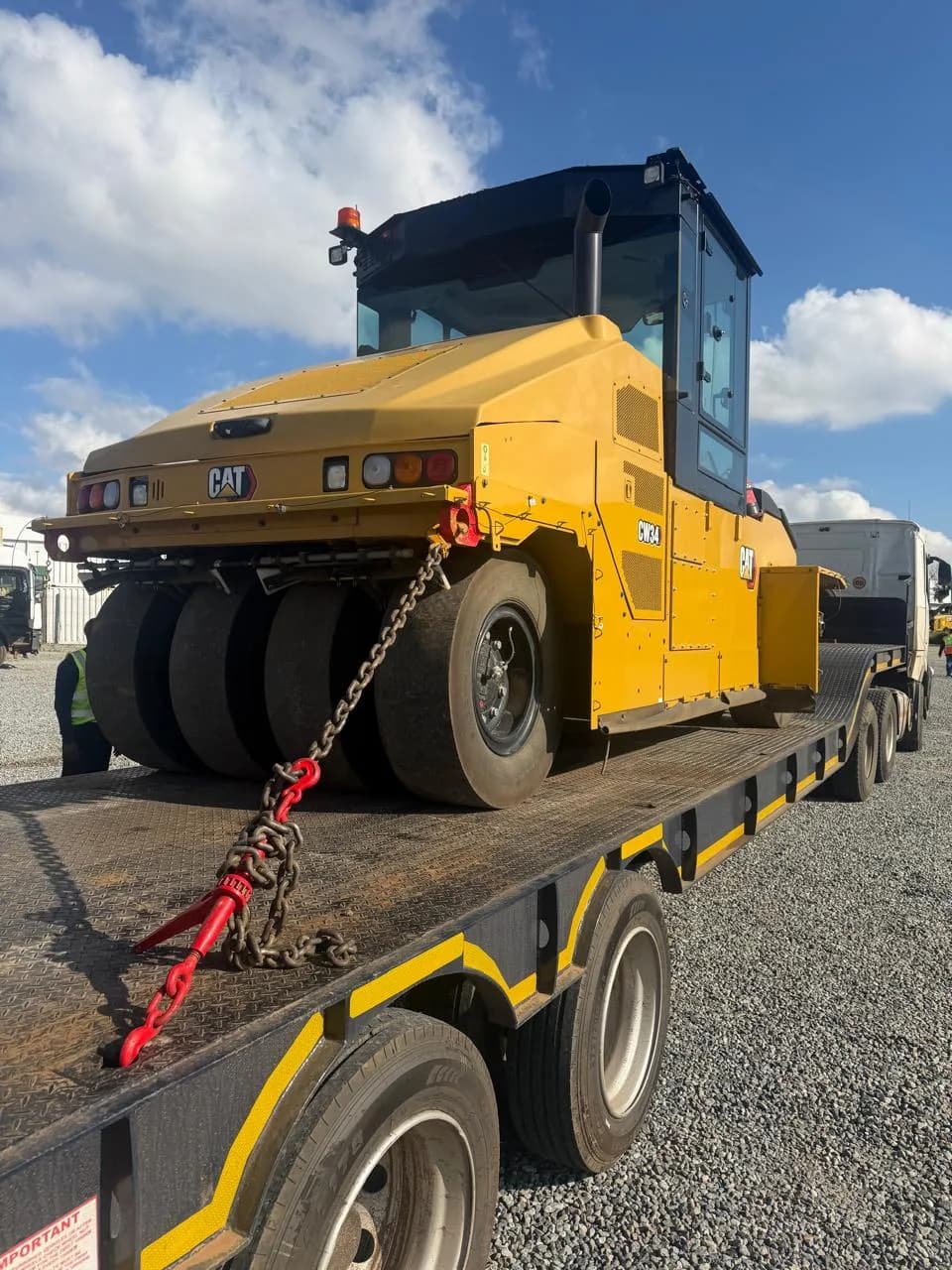 A Caterpillar CW34 pneumatic-tyre roller chained down on a lowbed trailer.